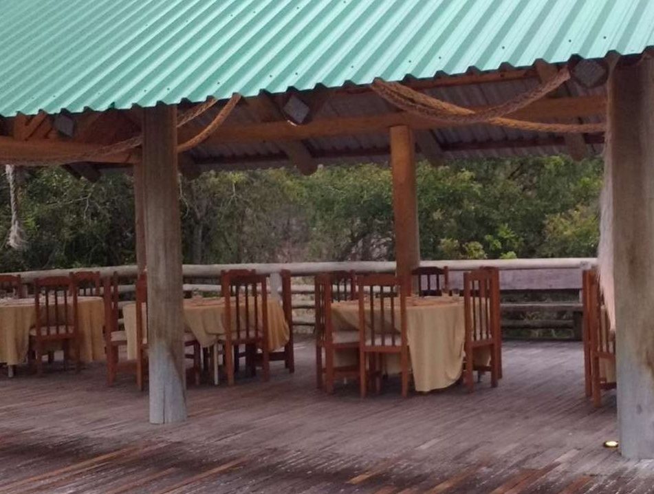 Quiosque coberto com mesas postas sobre deck de madeira